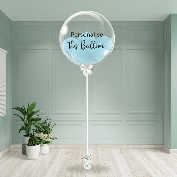 A gentle baby blue bubble balloon on a stand, ready to be personalised, offers a serene touch.