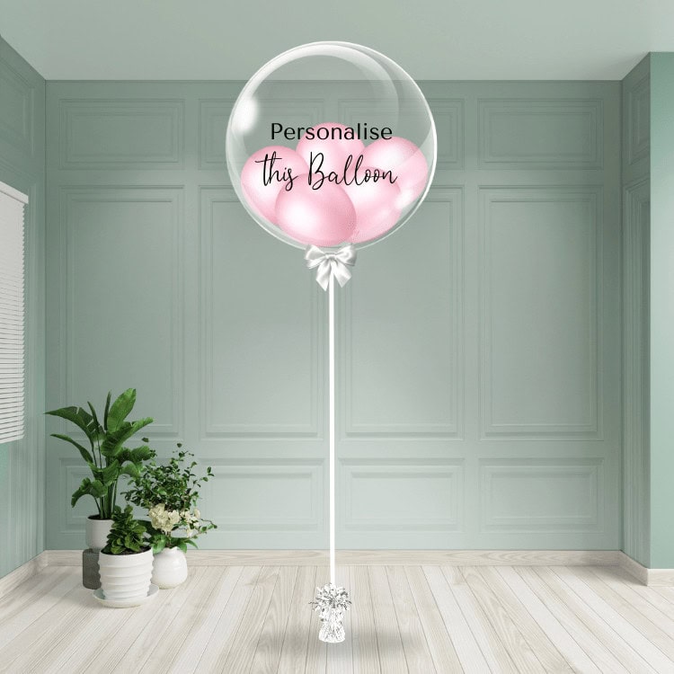 A delicate baby pink bubble balloon awaits personalisation, adding a sweet touch to the setting.