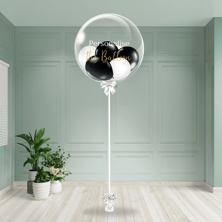 A stylish black and white bubble balloon with custom text, secured to an elegant base.