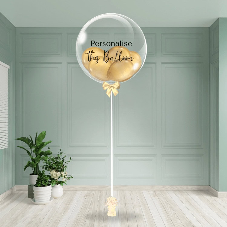 Gold chrome personalised bubble balloon tied with a golden ribbon in an elegant interior.