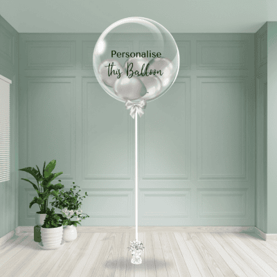 A shimmering silver chrome balloon with a customisable feature, poised on a chic stand amid a minimalist room setting.