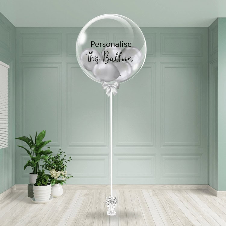 A shimmering silver chrome balloon with a customisable feature, poised on a chic stand amid a minimalist room setting.