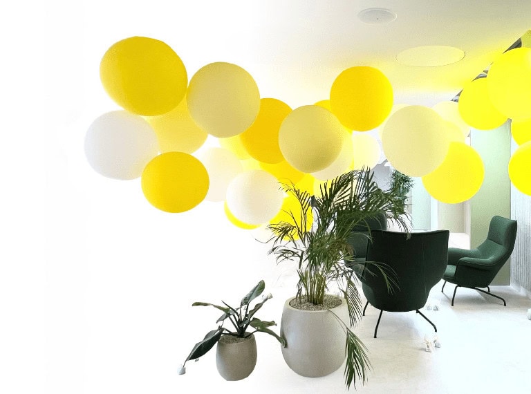 Oversized yellow balloons creating a dramatic ceiling decor in a chic room.