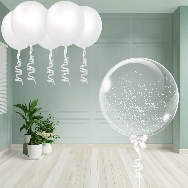 Snow globe-style clear balloon with white confetti and white ceiling balloons with ribbon tails.